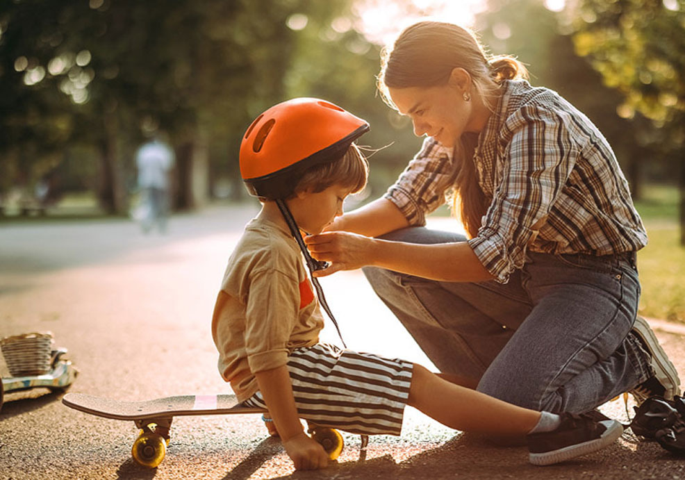 BPI Reforma Vida PPR 2060. Imagem de uma mãe sorridente, num parque, a colocar o capacete a uma criança.